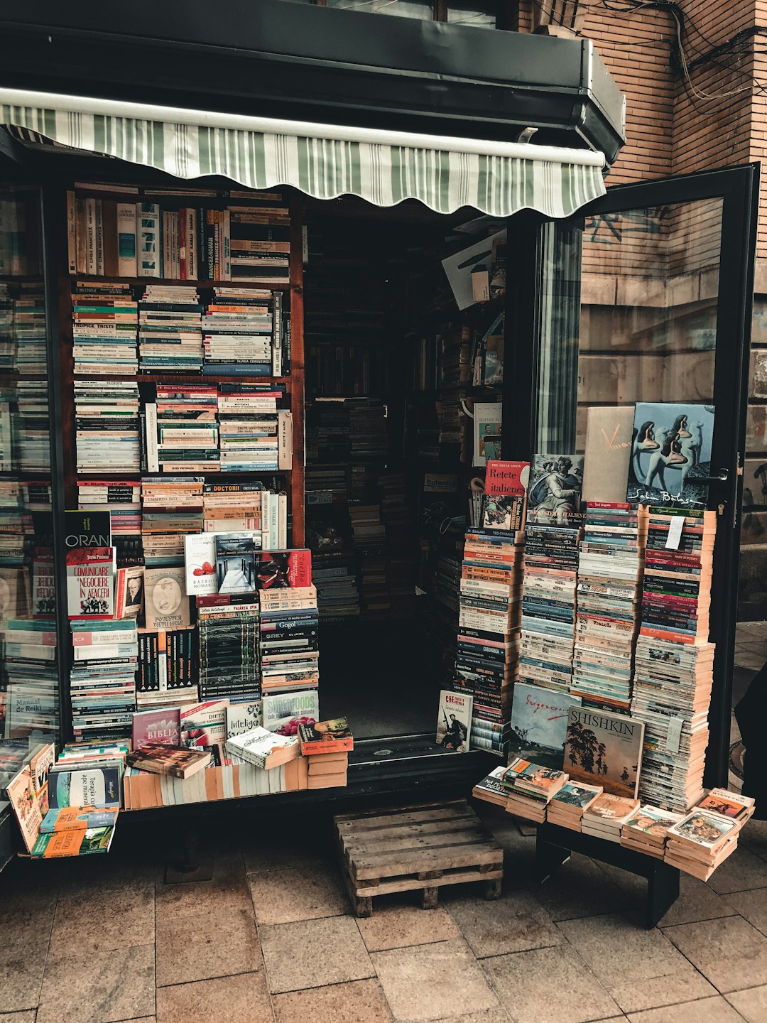 Traditional bookstore with book displays under a striped awning.
