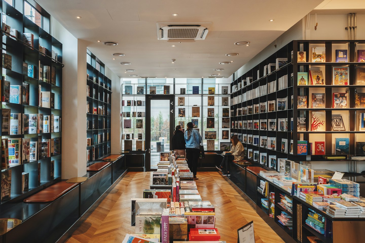 People browse shelves of books in a modern bookstore.